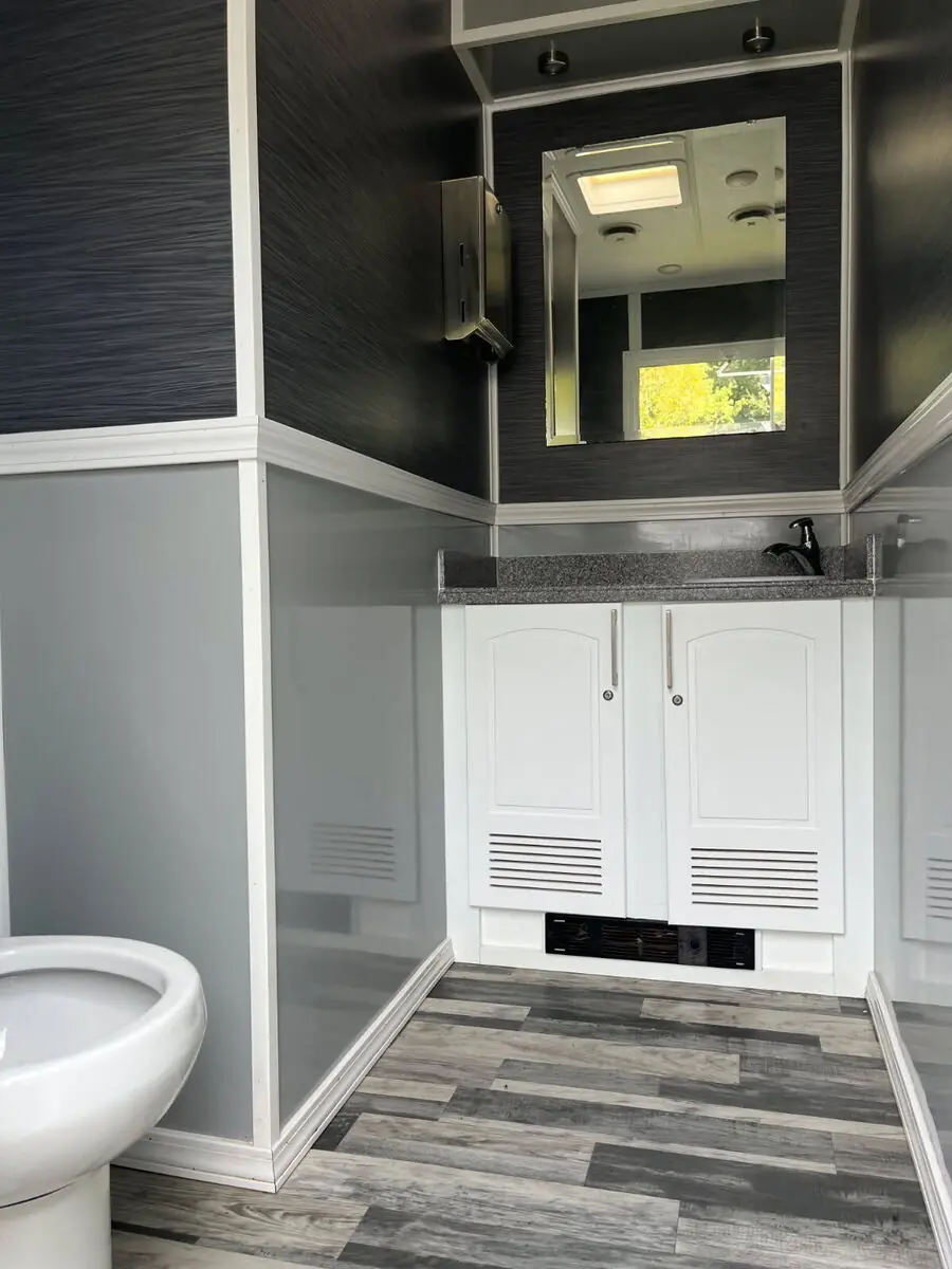 Restroom trailer room with running-water sink, framed mirror and designer flooring